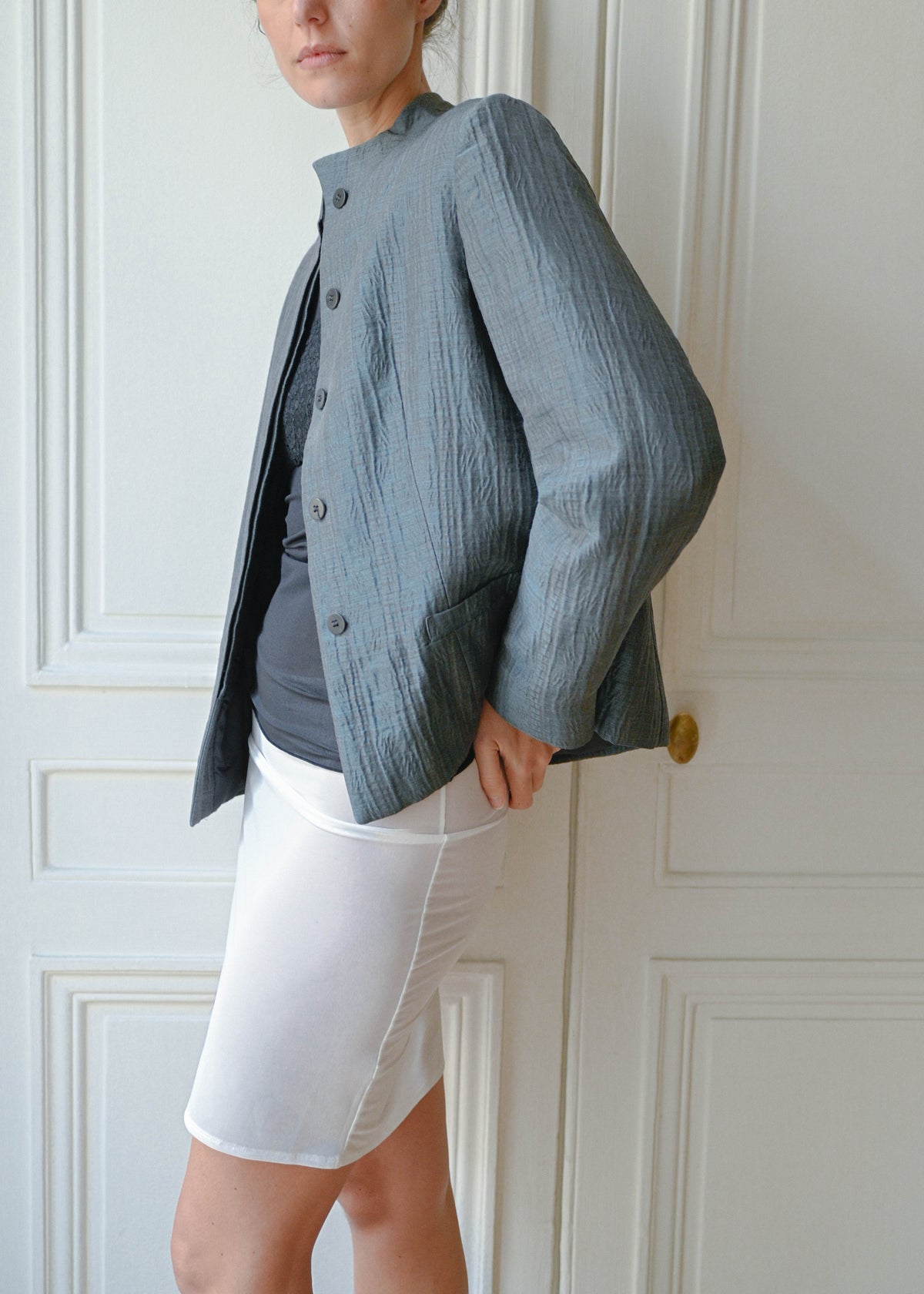 TURN Paris Under Skirt, sheer white knit skirt, three-quarter view, worn with a grey jacket