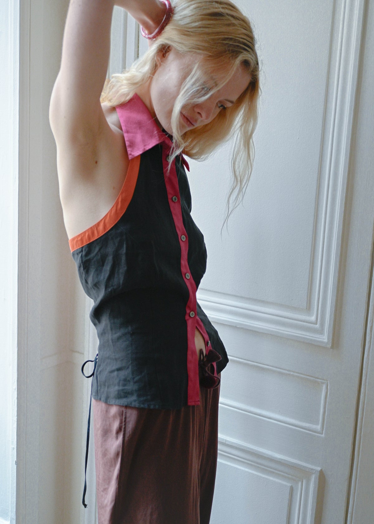 Vintage black silk sleeveless top with a pink collar, orange piping and an open back, close up, TURN Paris