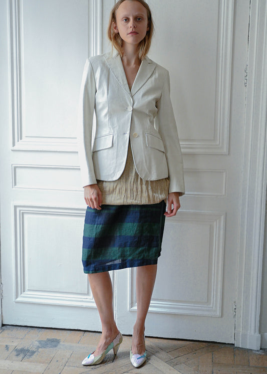 Cream leather jacket worn with gold textured mini dress and striped linen skirt, front view