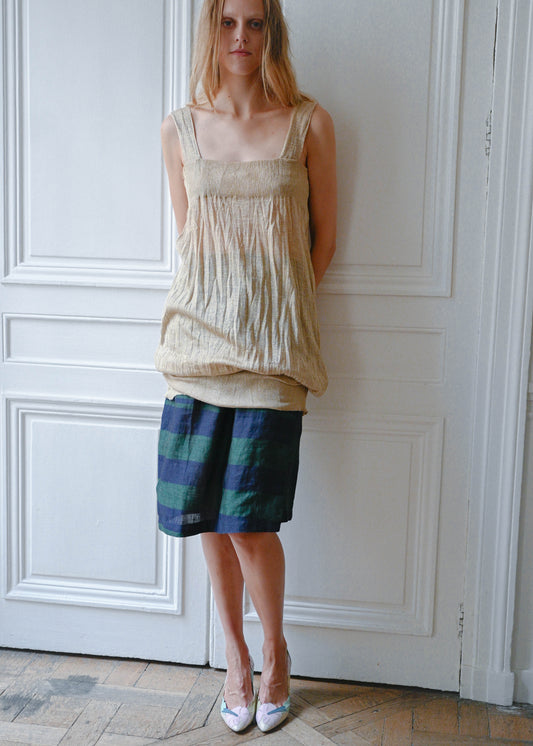 Gold textured mini dress worn over striped linen skirt, front view
