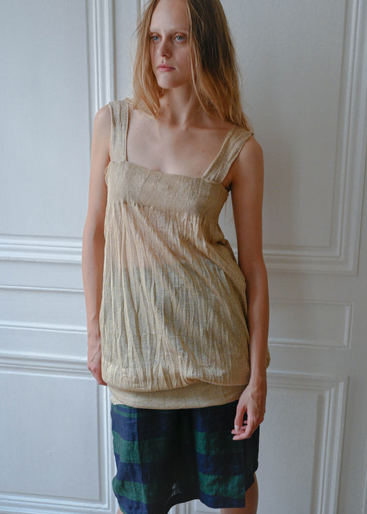 Gold textured mini dress worn over striped linen skirt, front view