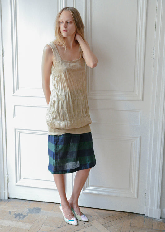 Gold textured mini dress worn over striped linen skirt, front view