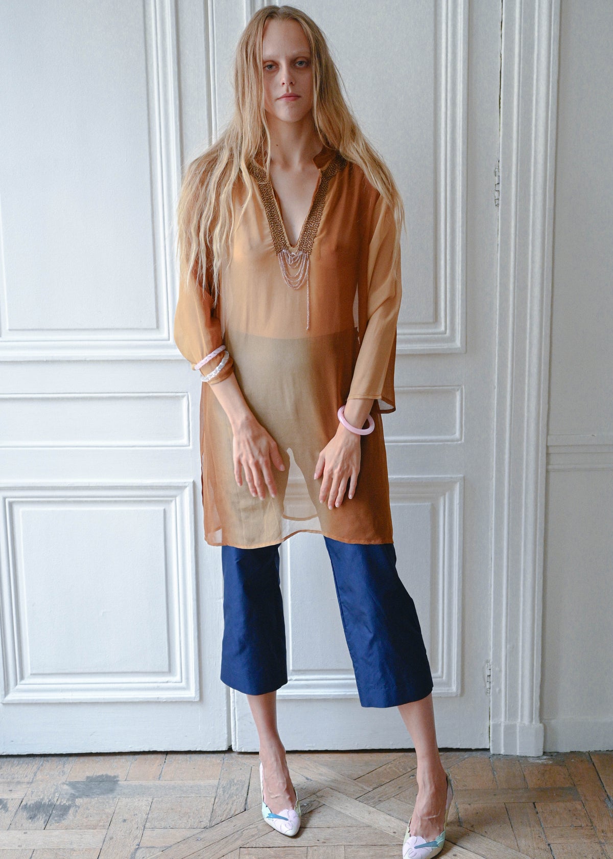 Bronze chain neck tunic worn with navy cropped trousers, front view