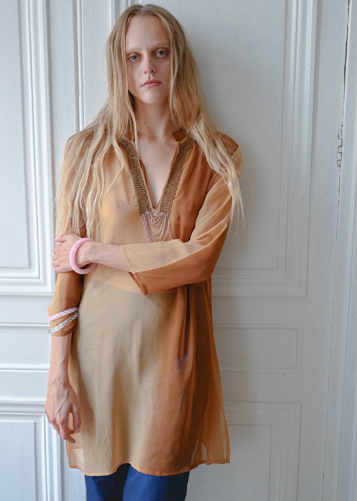 Bronze chain neck tunic worn with navy cropped trousers, front view
