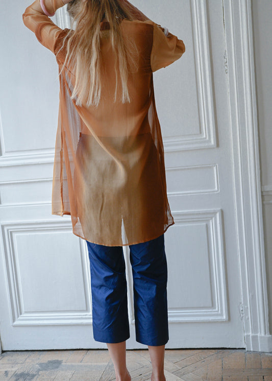 Bronze chain neck tunic worn with navy cropped trousers, back view