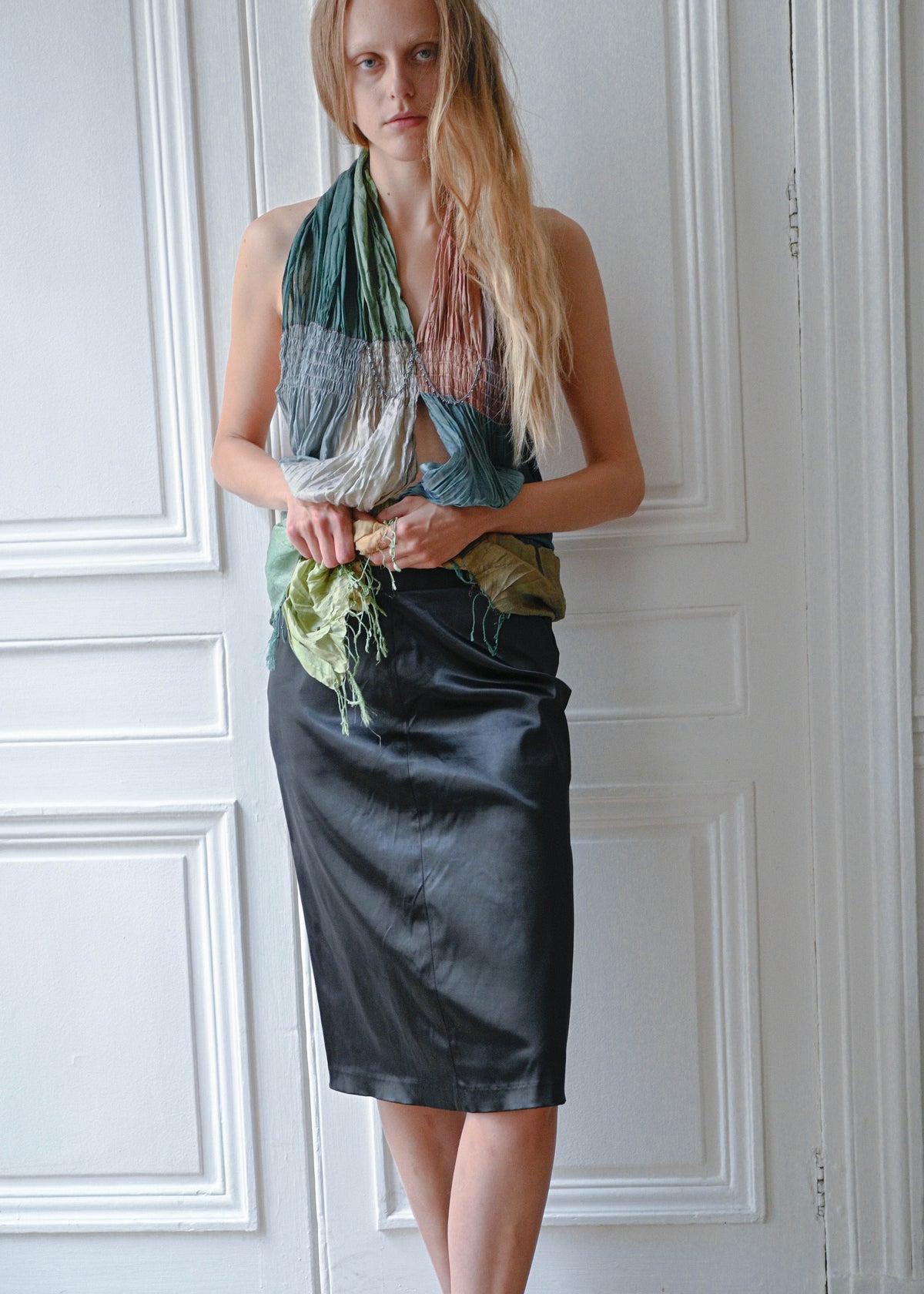 Black vinyl pencil skirt worn with metal mesh halter top, front view