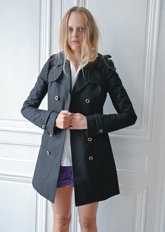 Black short trench coat worn over white cotton shirt and purple shorts, front view