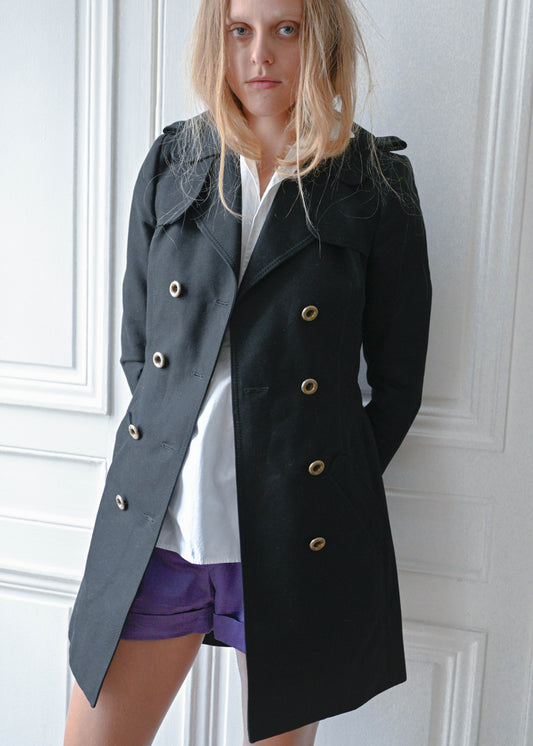 Black short trench coat worn over white cotton shirt and purple shorts, front view