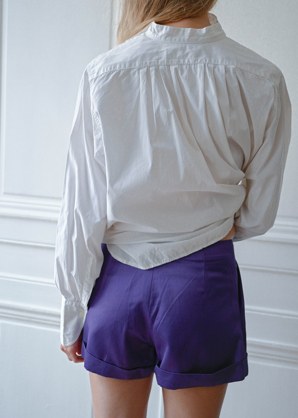 Purple shorts worn with white cotton shirt, back view