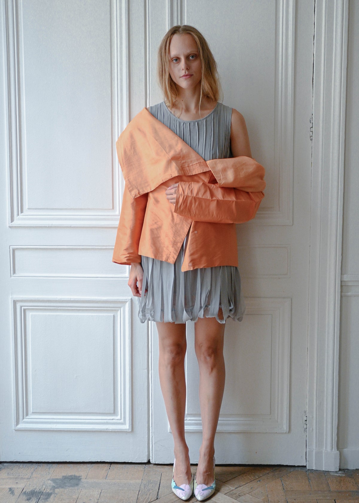 Orange draped silk jacket worn over grey silk fringe dress