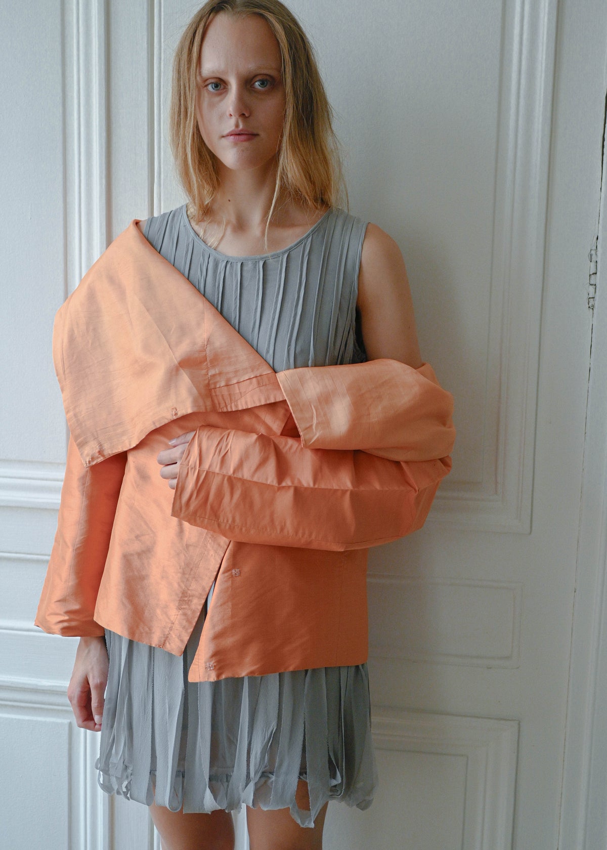 Orange draped silk jacket worn over grey silk fringe dress, front view