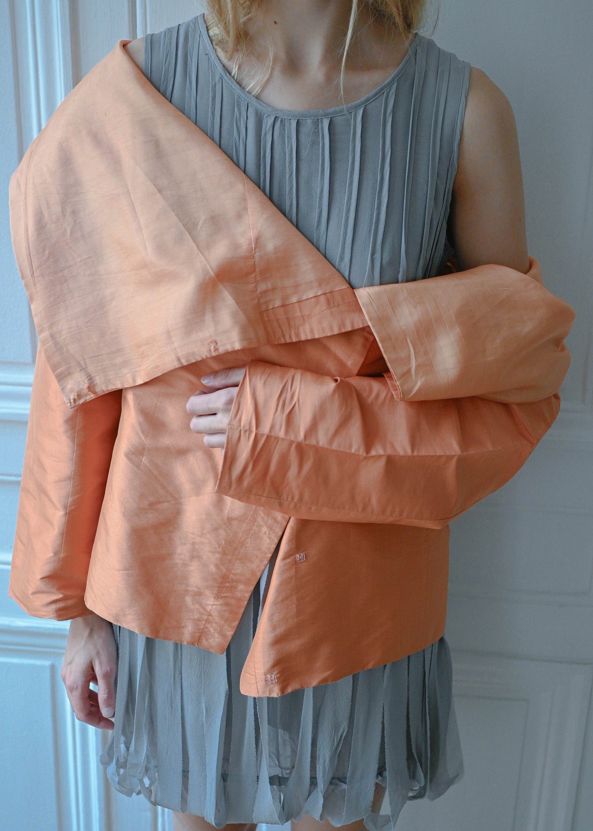 Orange draped silk jacket worn over grey silk fringe dress, close-up