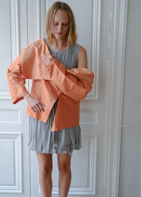 Orange draped silk jacket worn over grey silk fringe dress, close-up