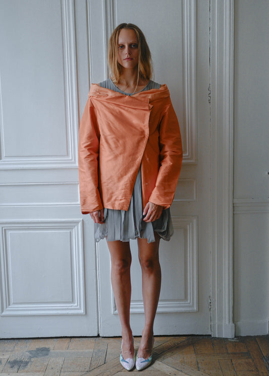 Orange draped silk jacket worn over grey silk fringe dress, front view