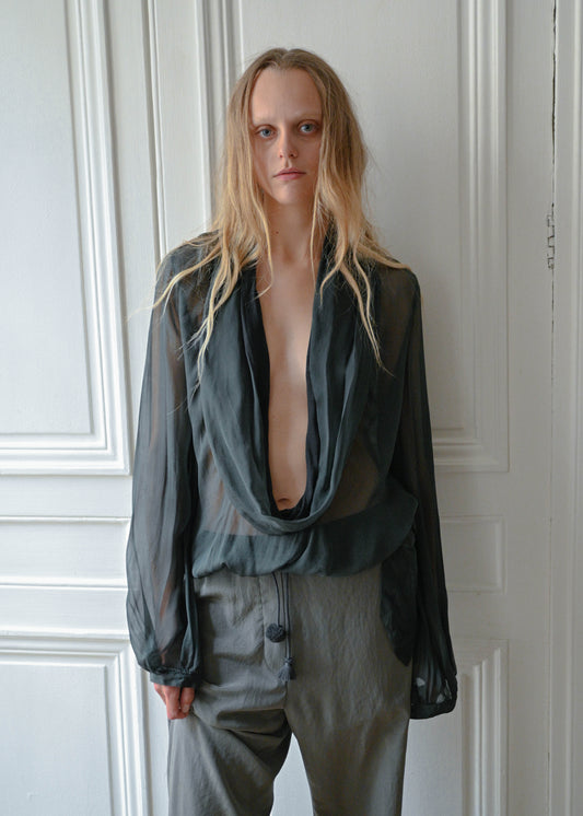 Green sheer draped blouse with a deep draped neckline, close-up
