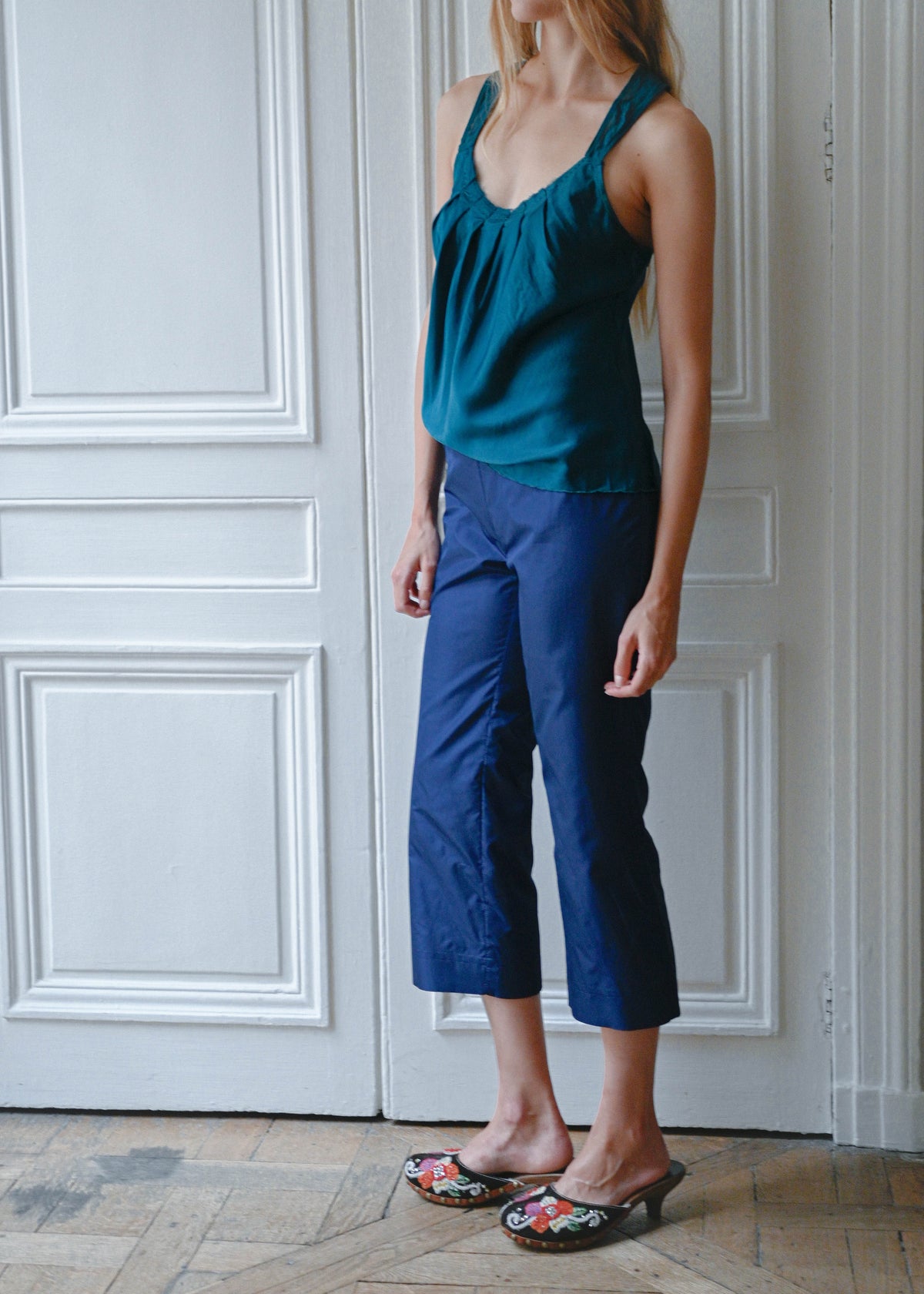 Turquoise silk cami worn with navy cropped trousers, front view