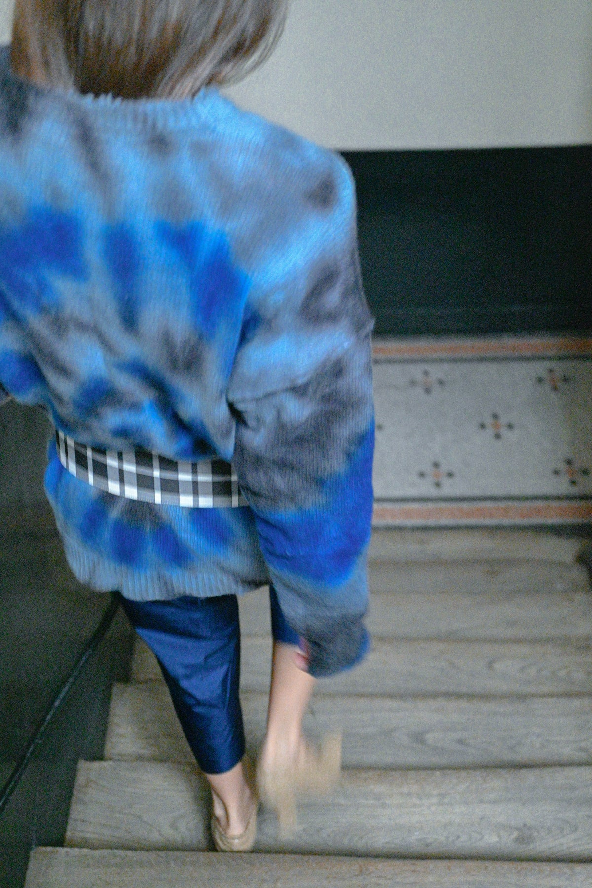 Tie-dye wool sweater worn with a checks belt, close-up