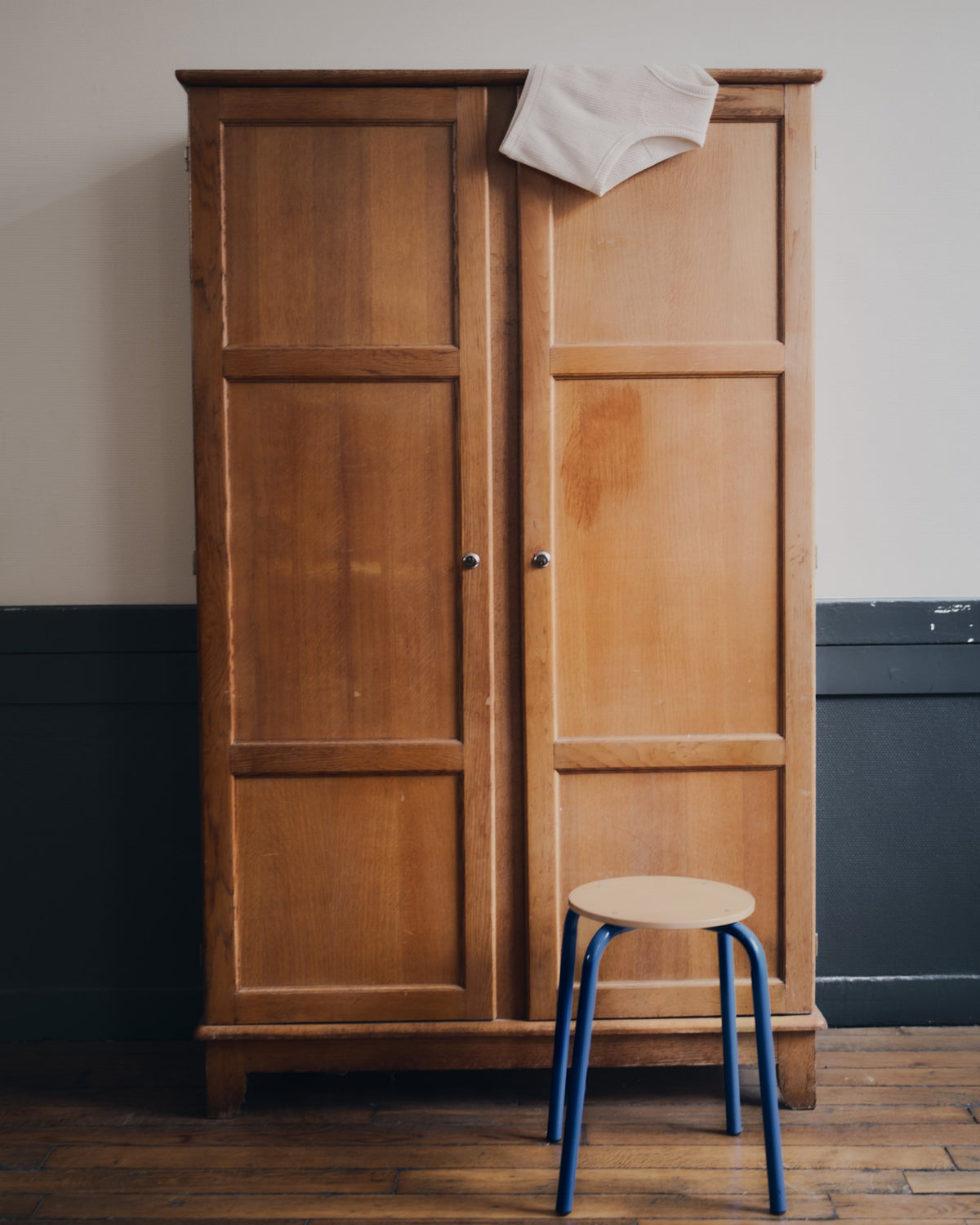 Wooden classroom wardrobe and blue stool, still life from the TURN Paris FW26 Paire collection